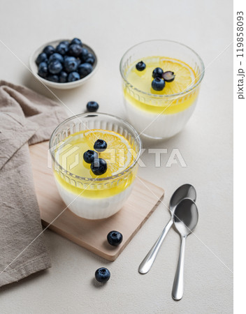 Creamy lemon panna cotta with blueberries in two glasses with fresh berries on a light background. Creamy lemon panna cotta with blueberries in two glasses with fresh berries on a light background. 119858093