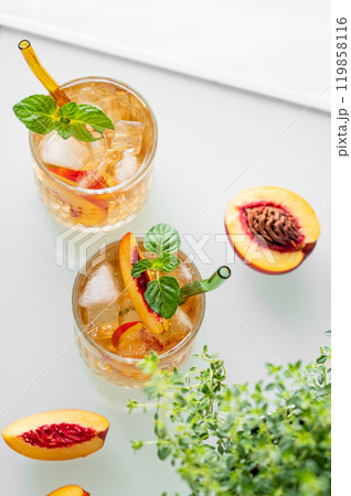 Peach lemonade with ice and mint on white background. Fresh iced tea in glasses Peach lemonade with ice and mint on white background. Fresh iced tea in glasses 119858116