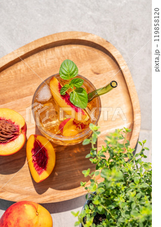 Peach lemonade with ice and mint on a wooden board on a concrete background. Fresh iced tea 119858120