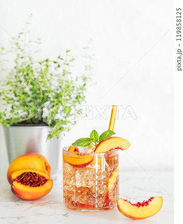 Peach refreshing drink with ice and mint on marble background. Fresh homemade lemonade in a glass 119858125