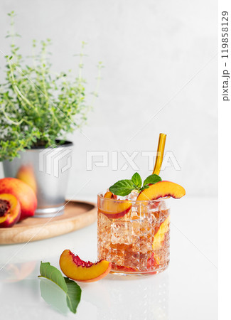Peach refreshing drink with ice and mint on a white background. Fresh homemade lemonade in a glass  119858129