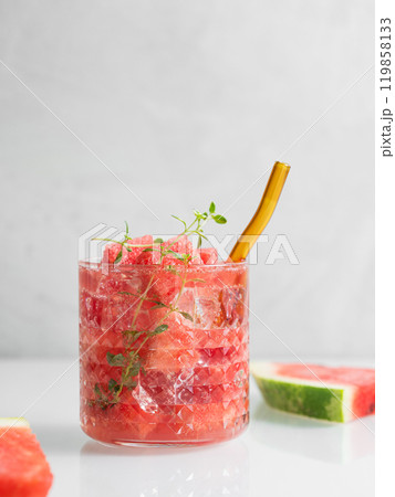 Refreshing watermelon cocktail in glass with thyme and ice on a light background with fresh fruits 119858133