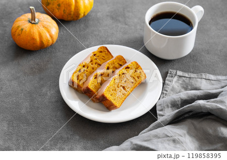 Pumpkin sweet bread or cake with icing on a plate on a dark background with decorative pumpkins Pumpkin sweet bread or cake with icing on a plate on a dark background with decorative pumpkins 119858395