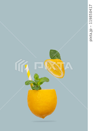 Juicy lemon with mint leaves and a paper straw in the form of a cup on a blue background. 119858417