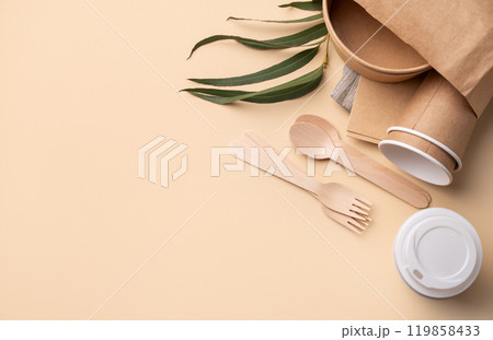Set of eco-friendly disposable tableware in paper bag with wooden cutlery, brown paper cups, bowls 119858433