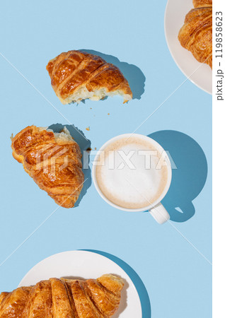 Flat lay of coffee cup and fresh croissants on blue background with shadow. Flat lay of coffee cup and fresh croissants on blue background with shadow. 119858623