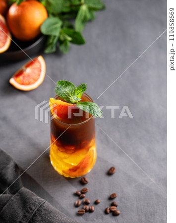 Coffee with orange juice (bumble) in a tall glass with ice and mint on a dark background 119858669