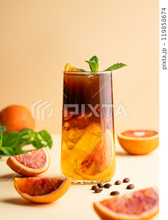 Americano coffee with orange juice (bumble) in a tall glass with ice and mint on a yellow background Americano coffee with orange juice (bumble) in a tall glass with ice and mint on a yellow background 119858674
