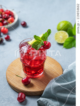 Cherry-lime mojito cocktail with mint, lime and ice on a wooden board on a blue background 119858682