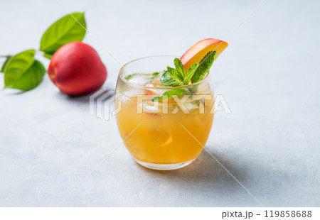 Refreshing peach cocktail, lemonade or iced tea in a glass on a light background. Refreshing peach cocktail, lemonade or iced tea in a glass on a light background. 119858688