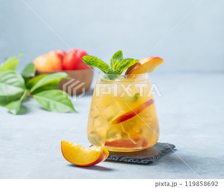 Refreshing peach cocktail, lemonade or iced tea in a glass on a light background. 119858692