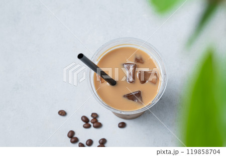 Iced coffee latte in a recyclable plastic glass with milk and ice on a light background Iced coffee latte in a recyclable plastic glass with milk and ice on a light background 119858704
