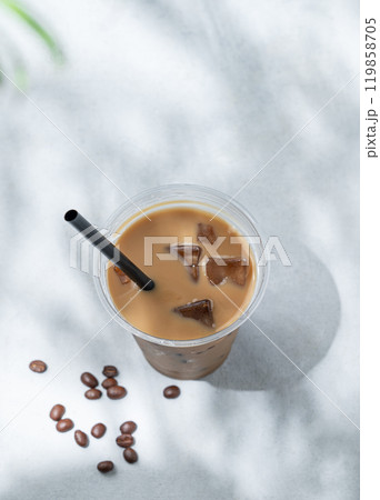 Iced coffee latte in a recyclable plastic glass with milk and ice on a light background  119858705