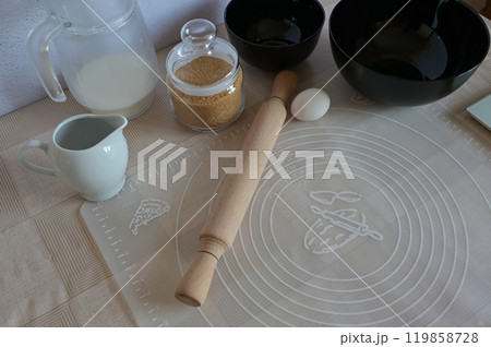 Baking ingredients for baking sweet buns in black bowl dishes with rolling pin on a table Baking ingredients for baking sweet buns in black bowl dishes with rolling pin on a table 119858728