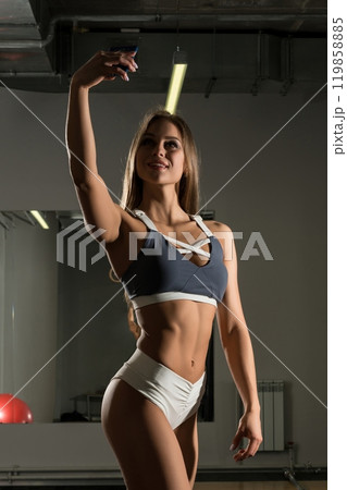 Pretty girl in gym with iphone full-length shot Pretty girl in gym with iphone full-length shot 119858885