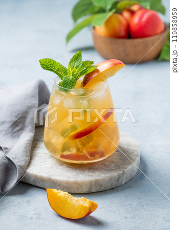 Refreshing peach cocktail, lemonade or iced tea in a glaa on a marble board on a light background. Refreshing peach cocktail, lemonade or iced tea in a glaa on a marble board on a light background. 119858959
