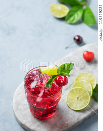 Cherry-lime mojito cocktail with mint, lime and ice on a marble board on a light background. Cherry-lime mojito cocktail with mint, lime and ice on a marble board on a light background. 119859223