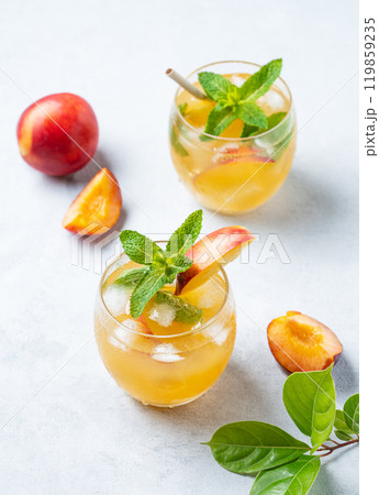 Two glasses with refreshing peach cocktail, lemonade or iced tea on a light background. 119859235