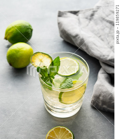 lime mojito with mint and ice in a glass. Refreshing citrus cocktail on a light background 119859271