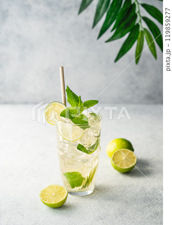 Mojito cocktail in a tall glass with lime, mint and ice on a light background.  119859277