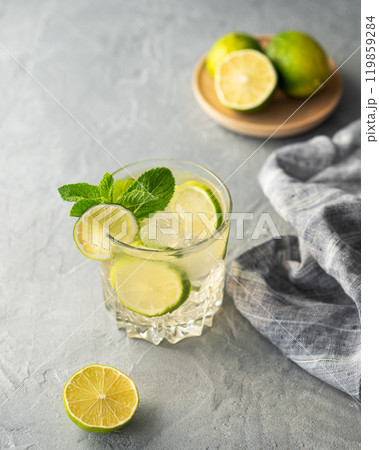 Lemonade drink with fresh lime on a texture background. Refreshing cocktail mojito Lemonade drink with fresh lime on a texture background. Refreshing cocktail mojito 119859284
