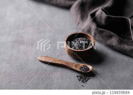 Black sesame seeds in a wooden bowl on a dark background with napkin. 119859684