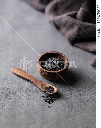 Black sesame seeds in a wooden bowl on a dark background with spoon. Black sesame seeds in a wooden bowl on a dark background with spoon. 119859685