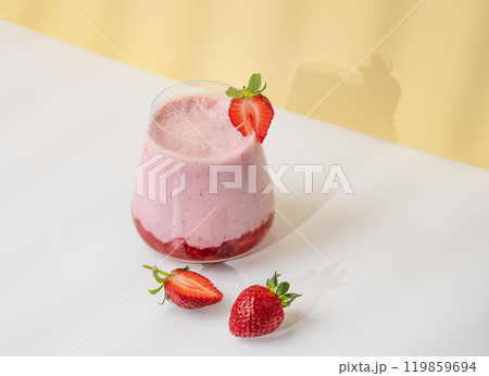 A strawberry milkshake or smoothie in a glass with strawberries on a yellow background A strawberry milkshake or smoothie in a glass with strawberries on a yellow background 119859694