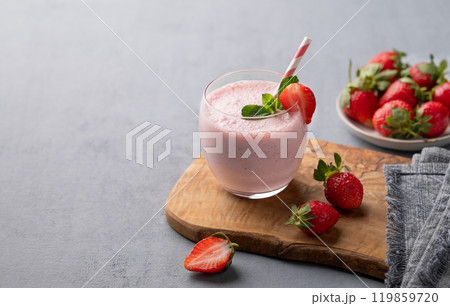 A glass of fresh strawberry smoothie with mint on a wooden board on a blue background  119859720