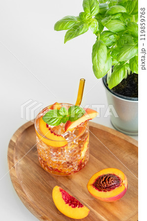 Peach refreshing drink with ice and mint on a wooden board on a white table. Fresh homemade lemonade 119859768