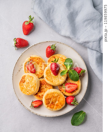 Cottage cheese, cheesecakes or syrniki with strawberries and mint leaves on a white plate Cottage cheese, cheesecakes or syrniki with strawberries and mint leaves on a white plate 119859975