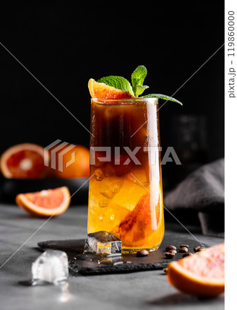 Coffee with orange juice (bumble) in a tall glass with ice and mint on a dark background 119860000