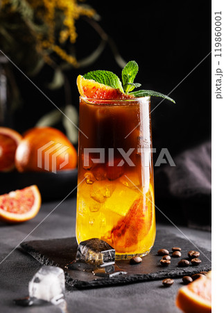 Coffee with orange juice (bumble) in a tall glass with ice and mint on a dark background 119860001