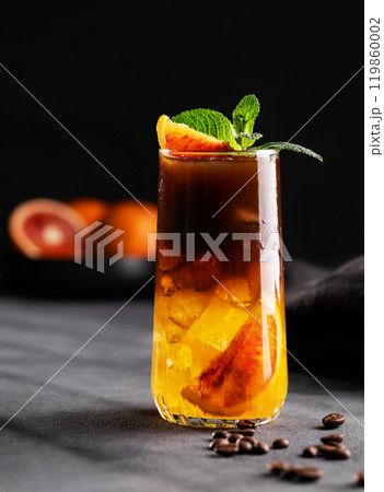 Coffee with orange juice (bumble) in a tall glass with ice and mint on a dark background 119860002