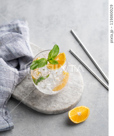 Lemonade tonic drink with fresh lemon, mint and ice on a marble board on a light background. Lemonade tonic drink with fresh lemon, mint and ice on a marble board on a light background. 119860029