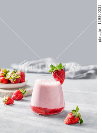 A glass of strawberry milkshake or smoothie with strawberries on a light background A glass of strawberry milkshake or smoothie with strawberries on a light background 119860033