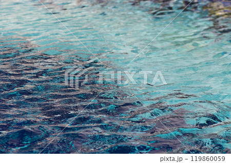 Gentle ripples dance on a tranquil blue water surface under the warm glow of sunlight at a serene coastal setting 119860059