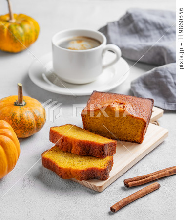 Pumpkin sweet bread with cinnamon on a wooden board on a light  background with decorative pumpkins 119860356