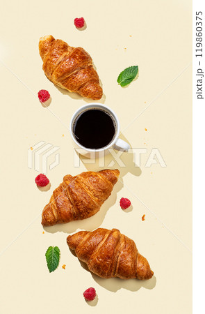 Flat lay of espresso coffee cup, fresh croissants, raspberry and mint leaf  on yellow background  119860375