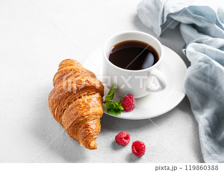 Cup of espresso coffee and croissant with fresh raspberries and mint on a plate  119860388