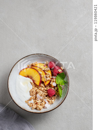 Greek natural yogurt with oat granola or muesli, peach, raspberry and mint in a bowl  119860421
