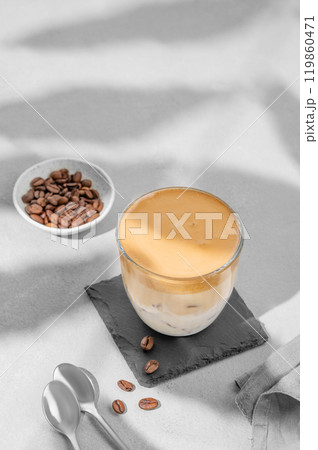 Dalgona coffee. Whipped instant coffee in a glass with ice on a slate board on a gray background Dalgona coffee. Whipped instant coffee in a glass with ice on a slate board on a gray background 119860471