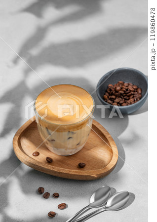 Iced dalgona coffee. Whipped instant coffee in a glass with ice on a wooden board Iced dalgona coffee. Whipped instant coffee in a glass with ice on a wooden board 119860478