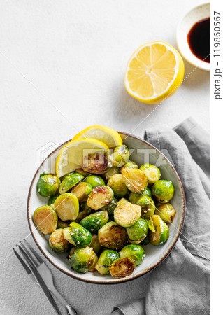 Fried brussels sprouts in a bowl with soy or balsamic sauce, lemon and sesame on a light background Fried brussels sprouts in a bowl with soy or balsamic sauce, lemon and sesame on a light background 119860567