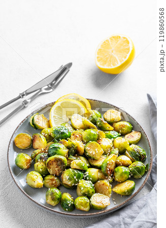 Crispy brussels sprouts in a plate with soy or balsamic sauce and sesame on a light background 119860568
