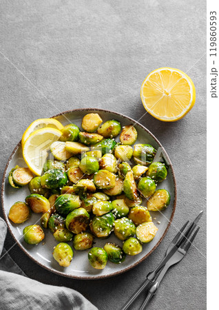 Fried brussels sprouts in a plate with soy or balsamic sauce and sesame on a dark background Fried brussels sprouts in a plate with soy or balsamic sauce and sesame on a dark background 119860593