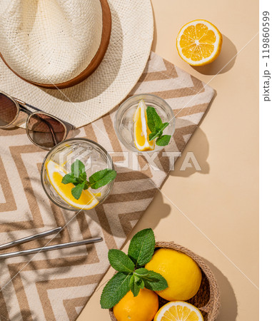 Summer layout with lemonade, fresh citrus fruits, hat and sunglasses on a beach towel  119860599