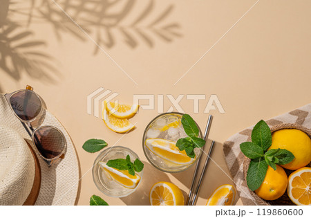 Summer layout with lemonade, fresh citrus fruits, hat and sunglasses on a beach towel Summer layout with lemonade, fresh citrus fruits, hat and sunglasses on a beach towel 119860600