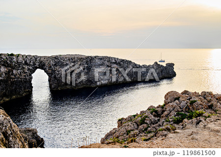 Spectacular sunset at Pont den Gil (Cala Corbetar) in Ciutadella, Menorca, Balearic Islands. Peculiar natural formation in the form of an arch 119861500