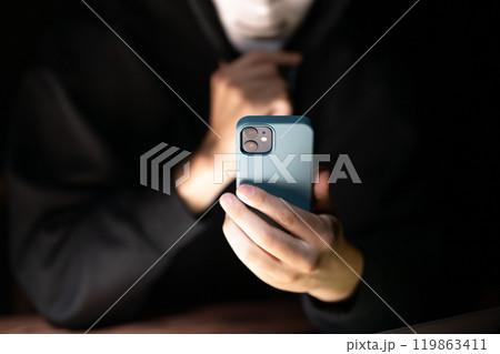 スマートフォンを操作する覆面ハッカー 119863411